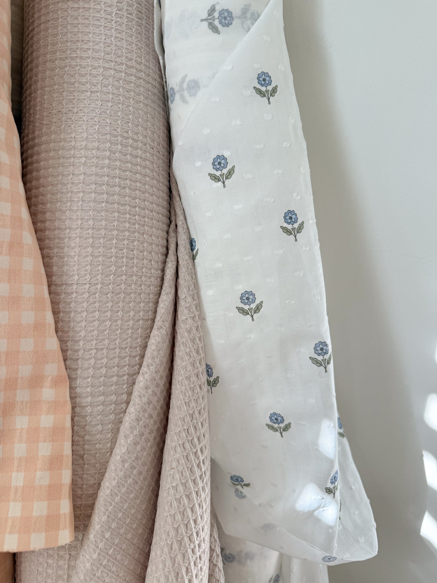 Collection of soft fabrics with different textures and patterns on a neutral background