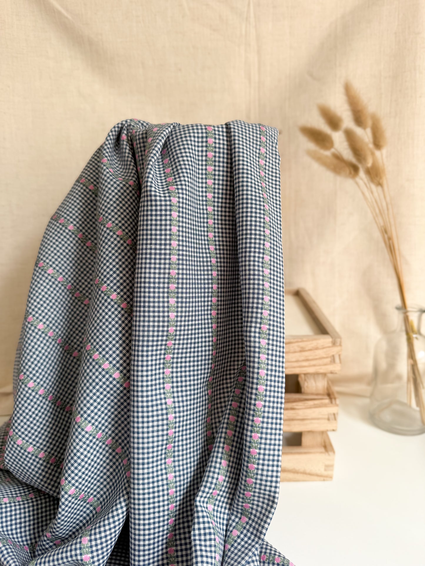 Checkered fabric with small patterns draped over a surface with a neutral background