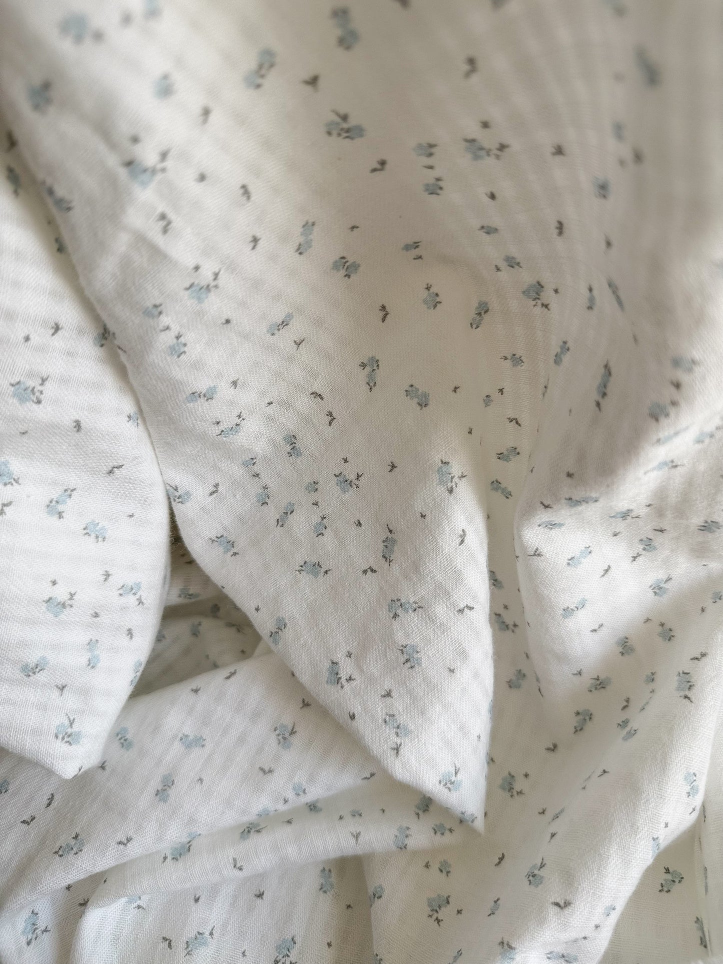 Close up on tiny blue floral print. Organic Cotton seesucker textured fabric.