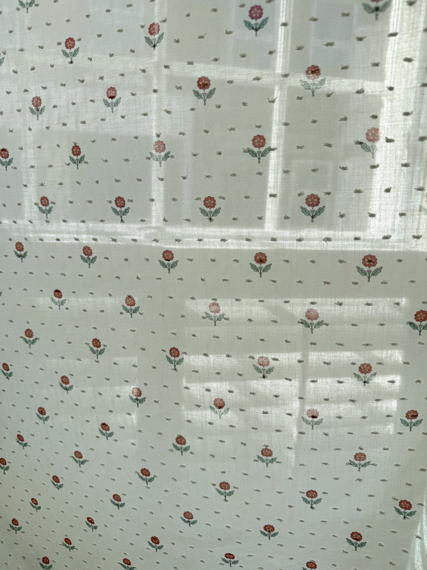 White fabric with small red floral patterns on a white background