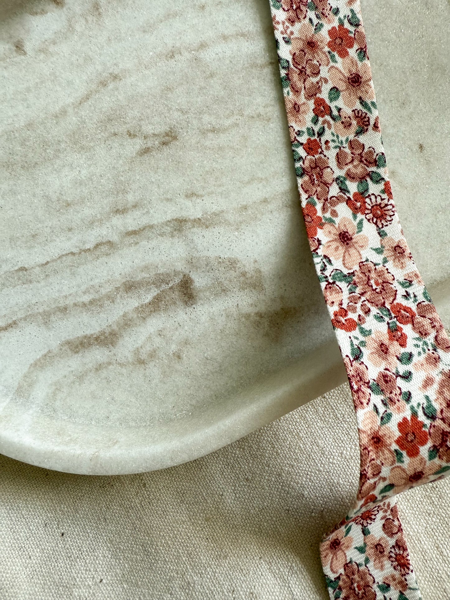 A close up image of an organic bias binding tape made with a pink ditsy floral fabric