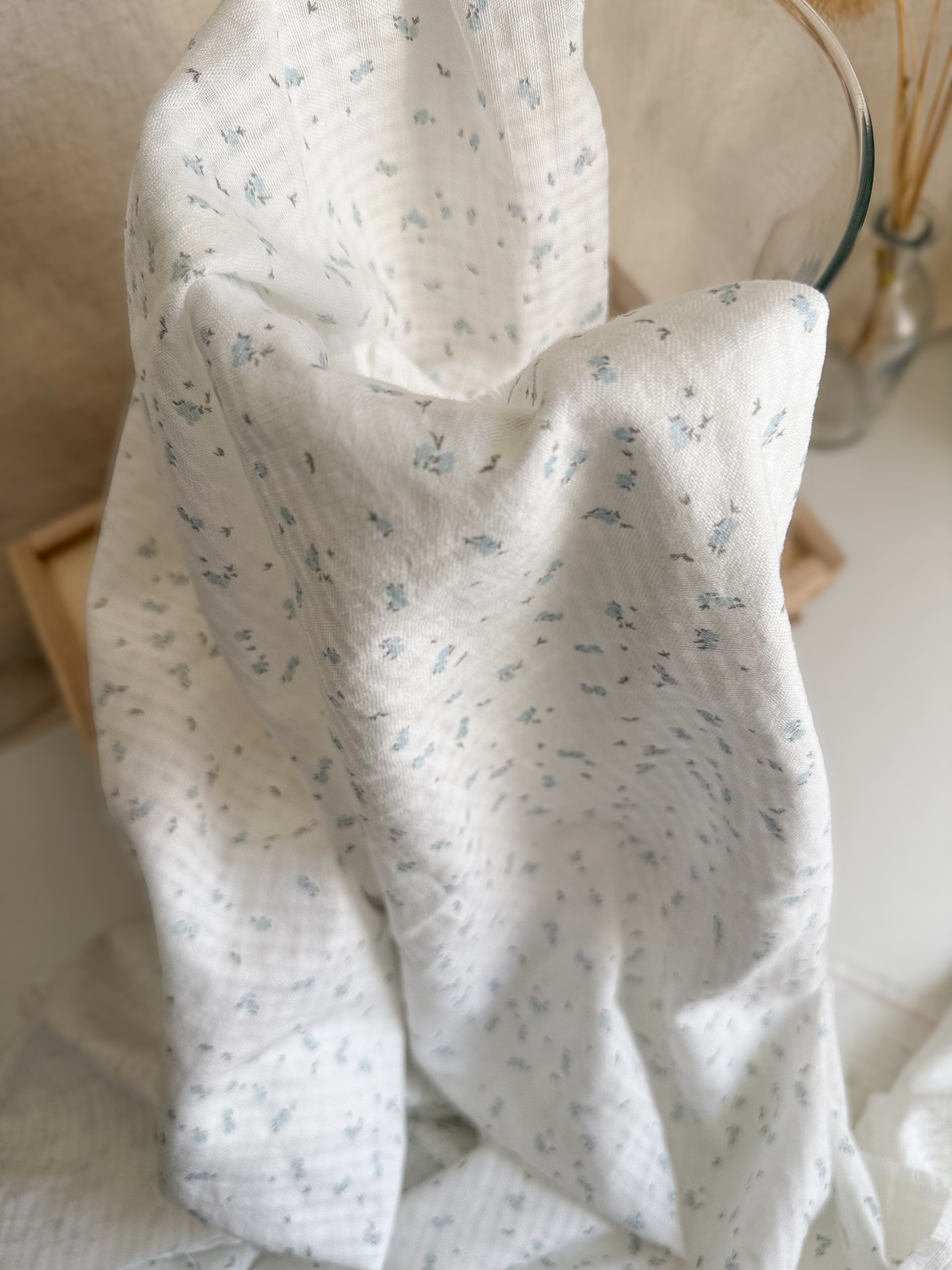 Textured GOTS organic cotton fabric with blue flower print on white background. 