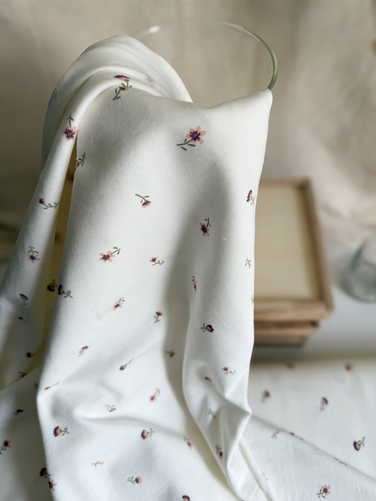 A pretty off-white cotton jersey fabric with ditsy purple and pink flowers