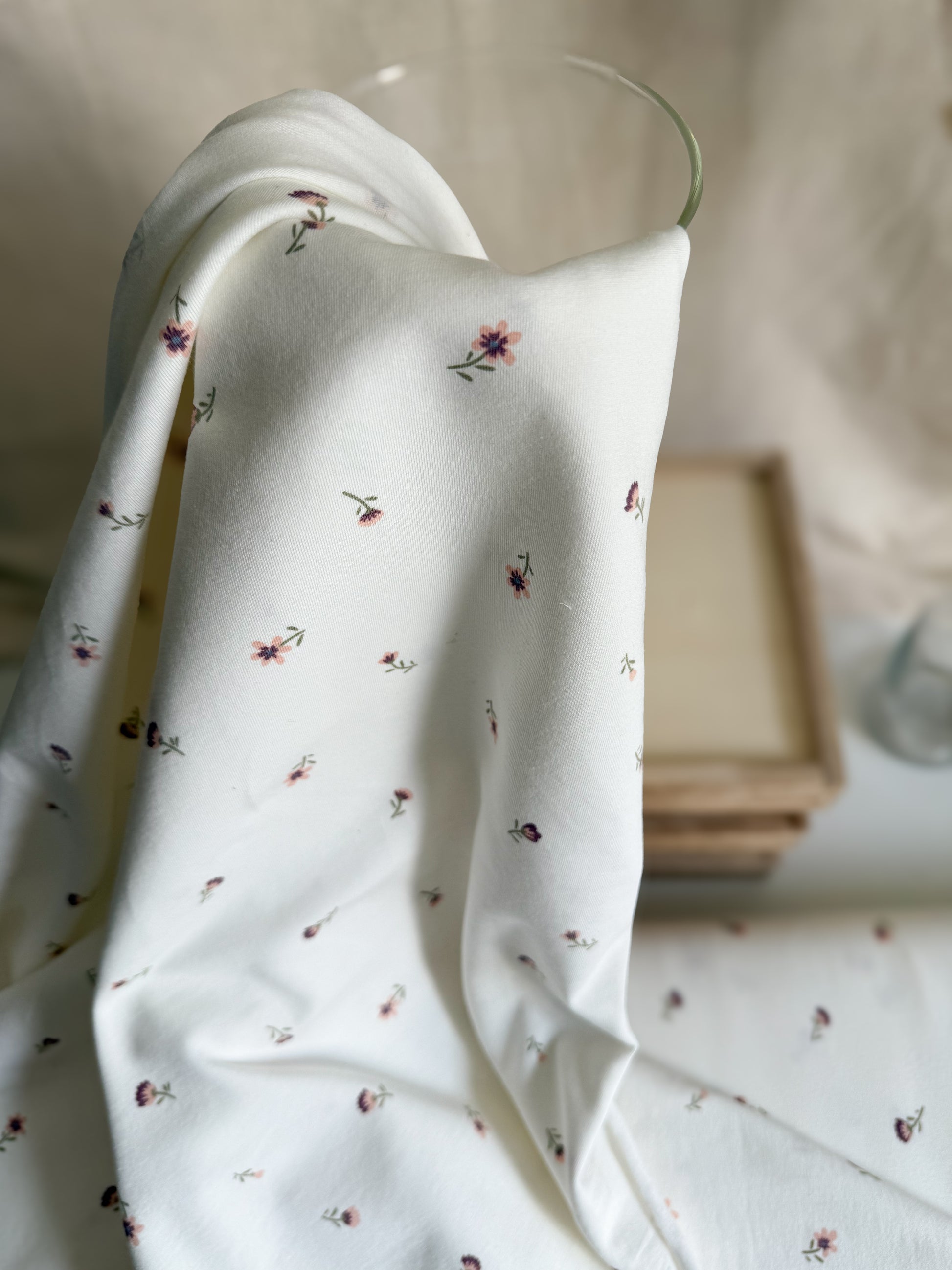 A pretty off-white cotton jersey fabric with ditsy purple and pink flowers