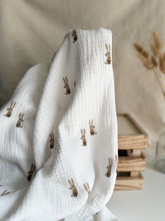 A lightweight double gauze fabric with cute bunny rabbit print on and off-white background