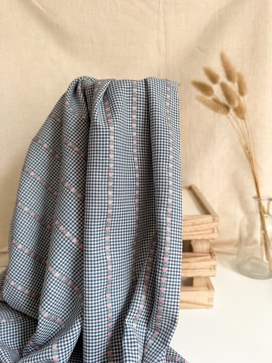 Checkered fabric with small patterns draped over a surface with a neutral background