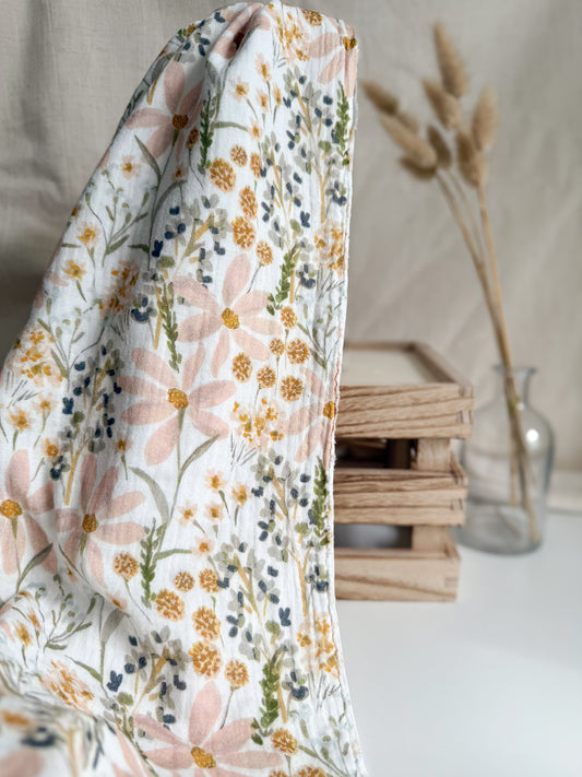 A watercolour floral double gauze muslin print fabric with soft pink and mustard tones
