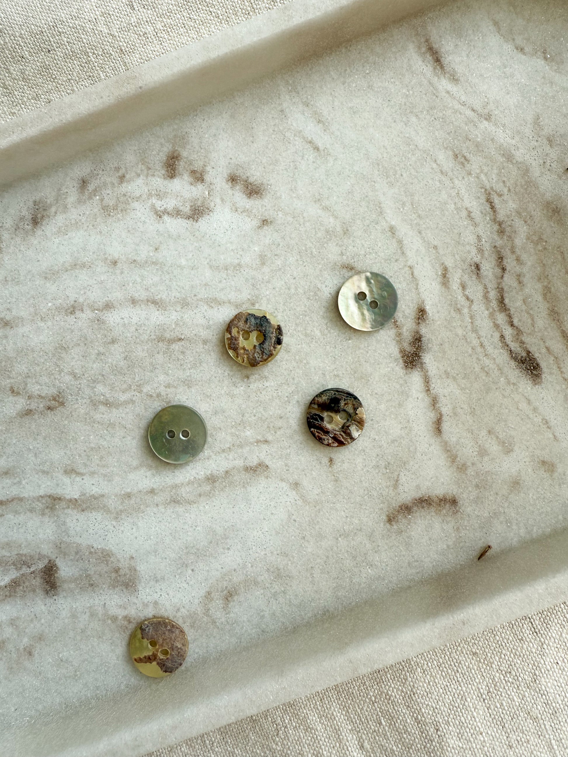 11mm, 13mm, 15mm mother of pearl button with two holes. Displaying the natural finish on the face and back side. 