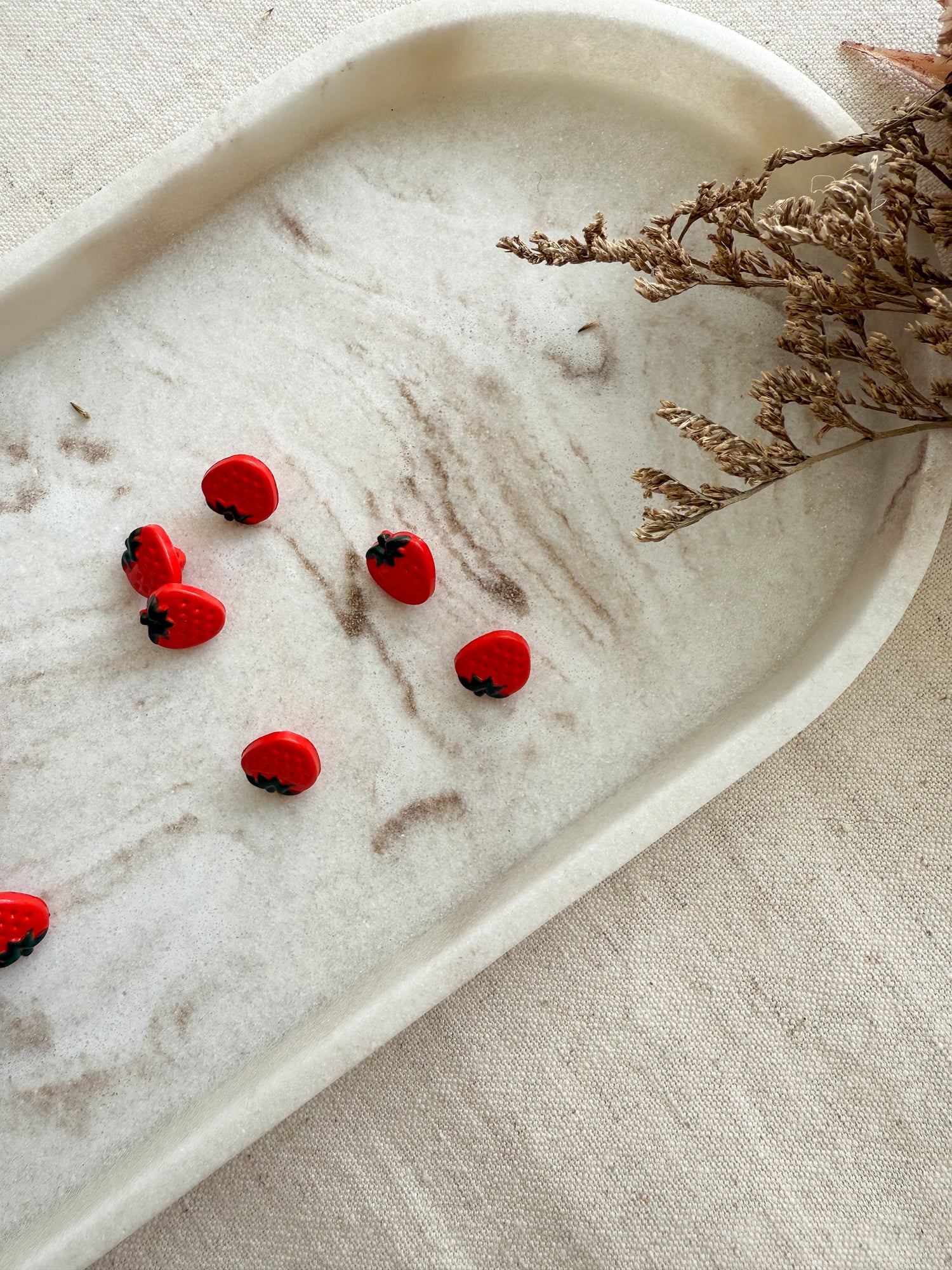 A vibrant red strawberry shaped small sewing button
