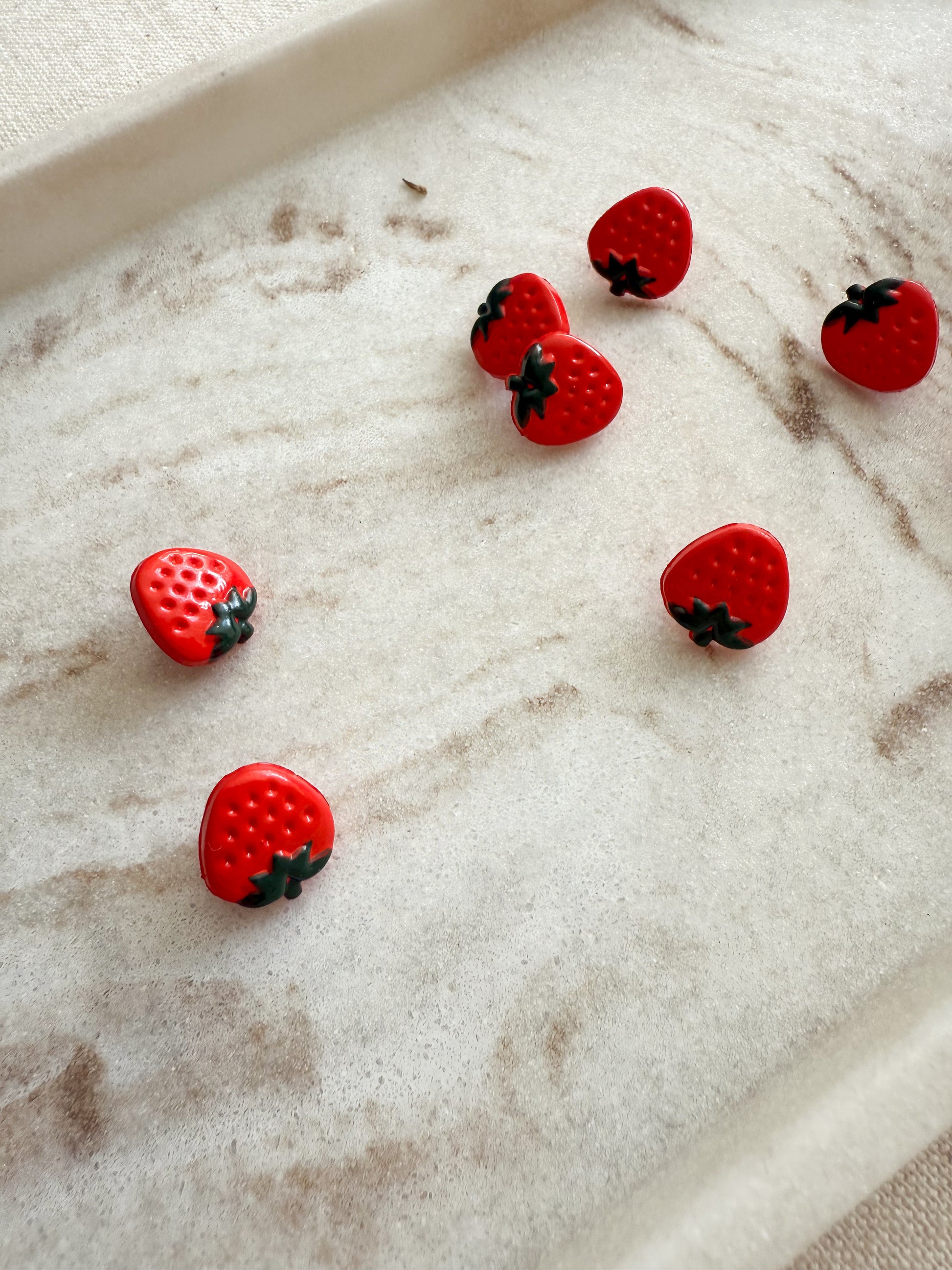 A vibrant red strawberry shaped small sewing button